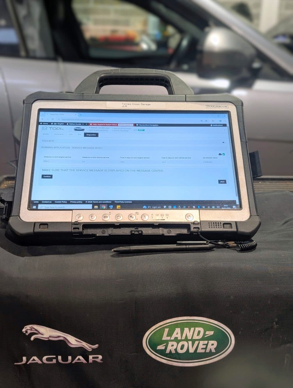 A dealer-level diagnostic laptop connected to a Jaguar Land Rover vehicle in the workshop